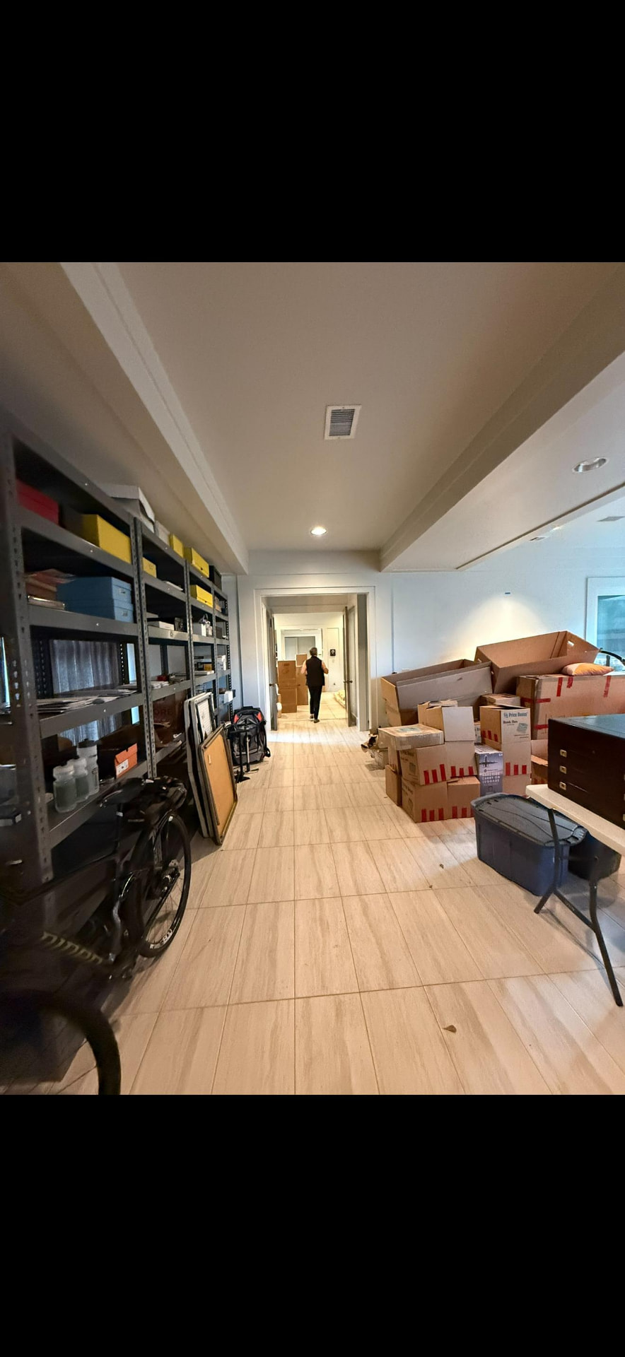 Wide interior gallery hall with storage shelving and stone tile floor