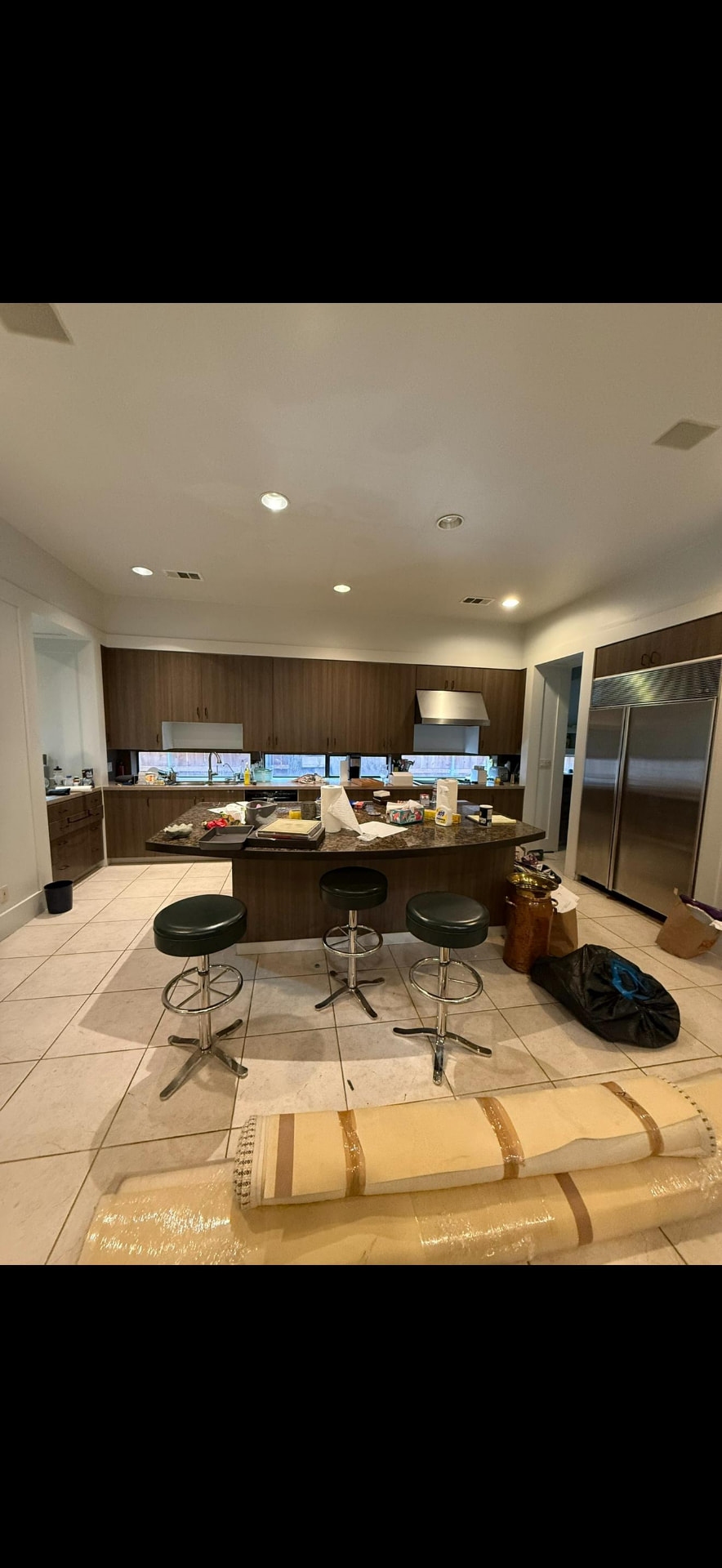 Existing kitchen with curved granite island, walnut cabinetry, and tile floor